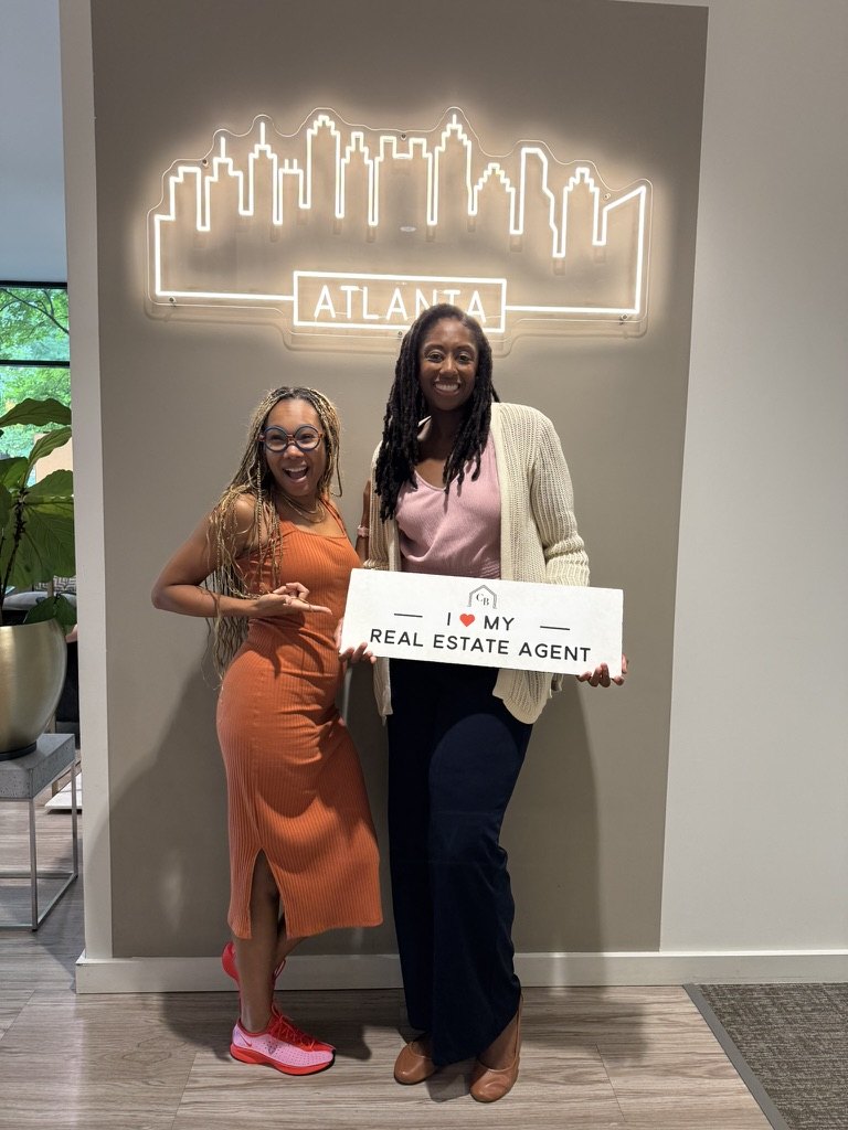 Happy clients holding a &lsquo;We love our real estate agent&rsquo; sign with Austin Walker
