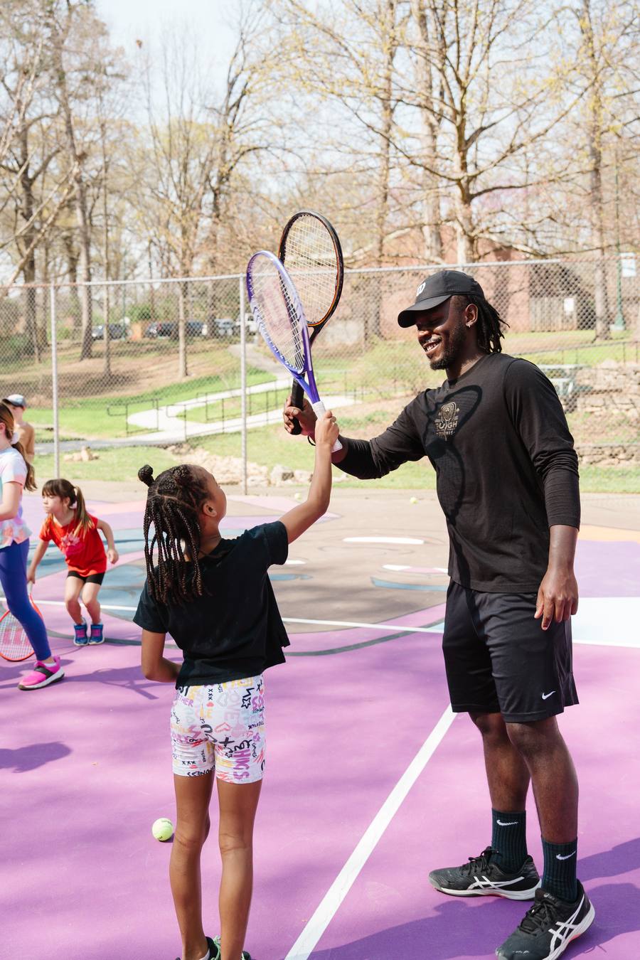 Coach high-fiving a young player at an EAV tennis clinic