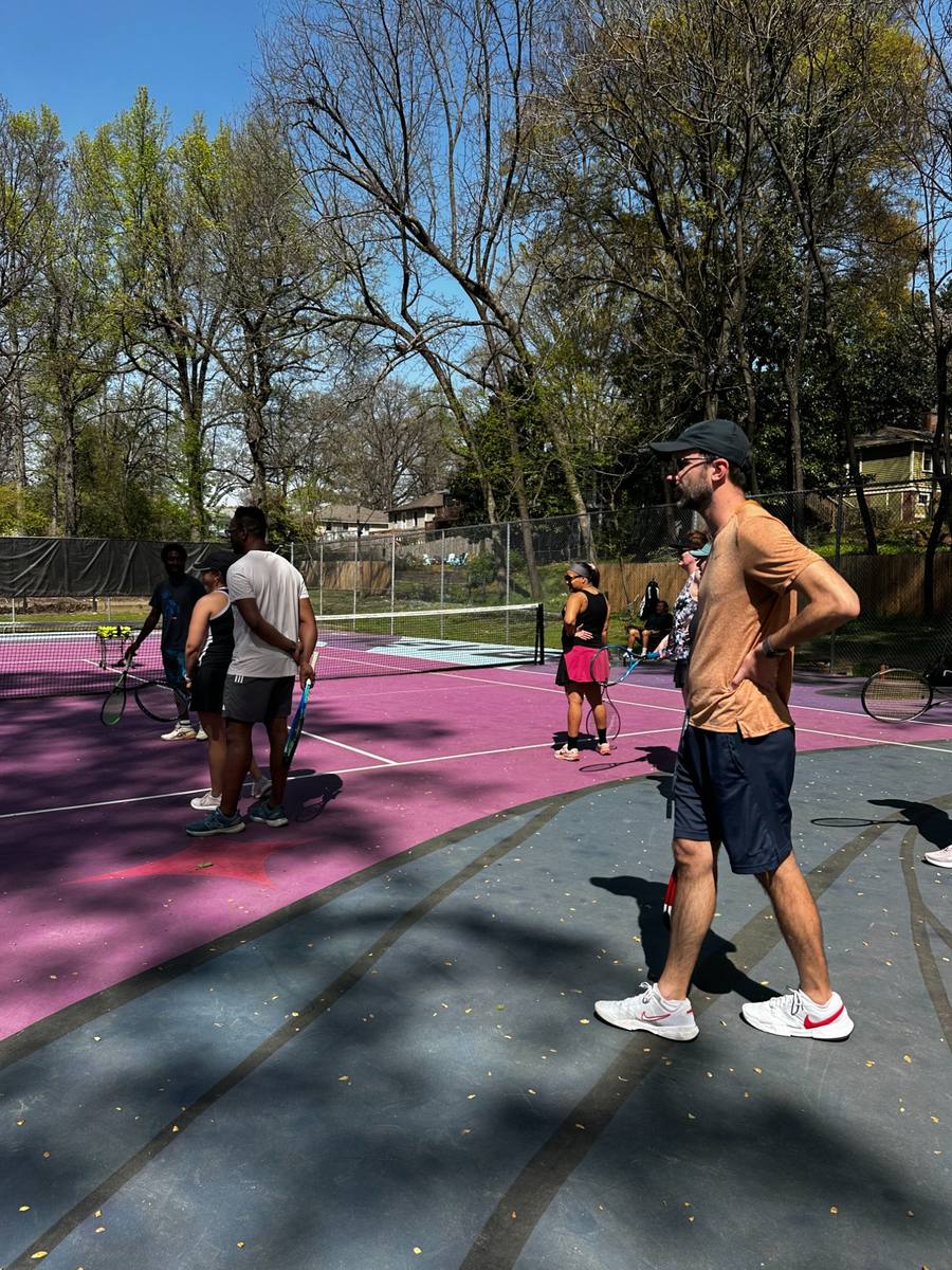 Neighbors playing tennis together on the colorful EAV courts